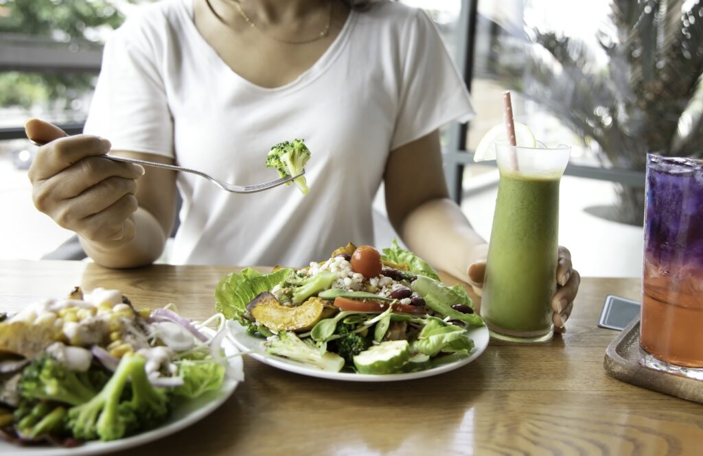 selective focus of woman with broccoli and salad which she make a intermittent fasting with a healthy food of salad and detox drink ,healthy lifestyle concept.